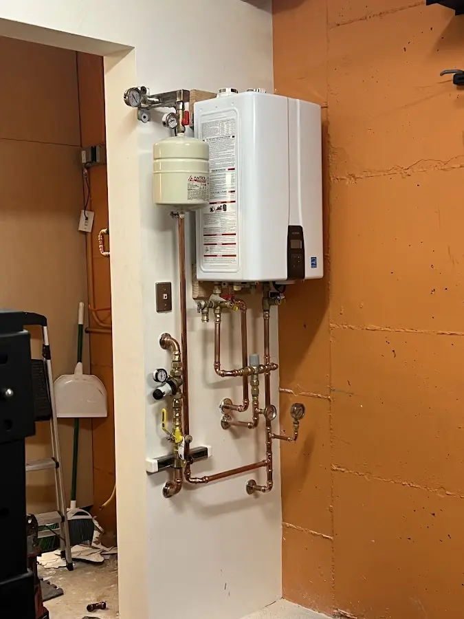 Plumbing technician inspecting water heater connections in DeKalb